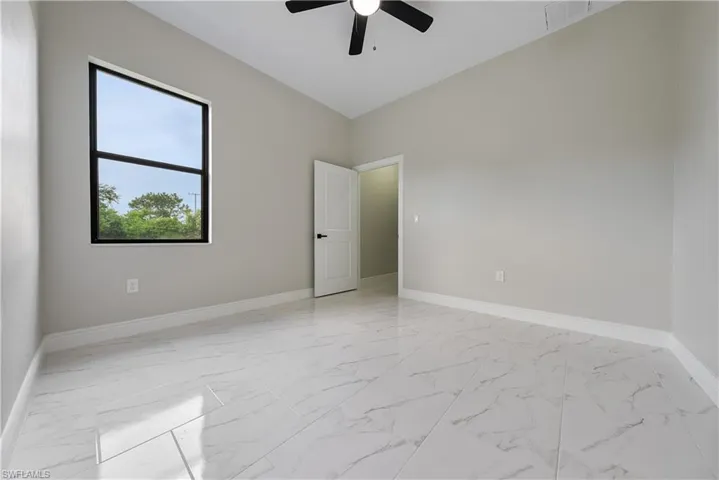 Spare room featuring light marble finish floors and a ceiling fan