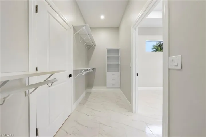 Walk in closet with light marble finish flooring