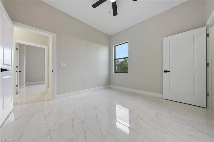 Unfurnished room featuring light marble finish floors, a ceiling fan, and vaulted ceiling