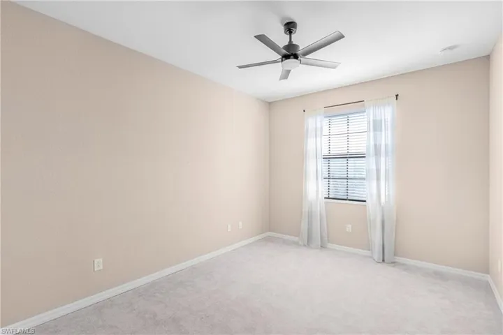 Empty room featuring light colored carpet and ceiling fan