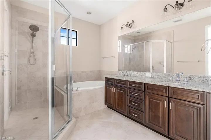 Full bath with double vanity, a garden tub, and a shower stall