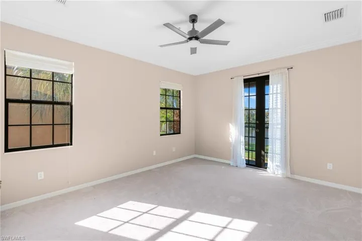 Carpeted empty room with healthy amount of natural light, a ceiling fan, and crown molding