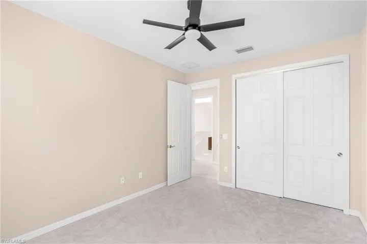 Unfurnished bedroom with a ceiling fan, light carpet, and a closet