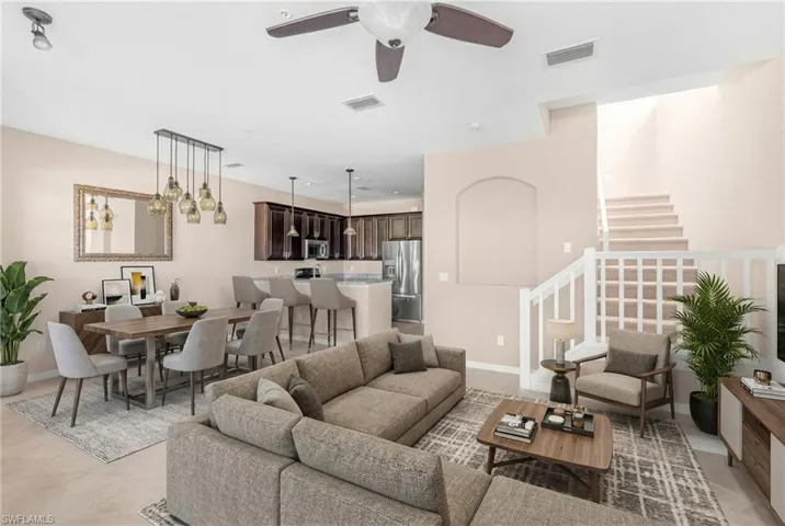 Living room with a ceiling fan, stairs, a chandelier, and light tile patterned flooring