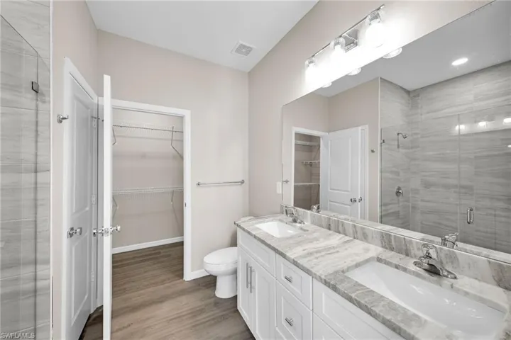 Bathroom with vanity, hardwood / wood-style flooring, toilet, and a shower with door