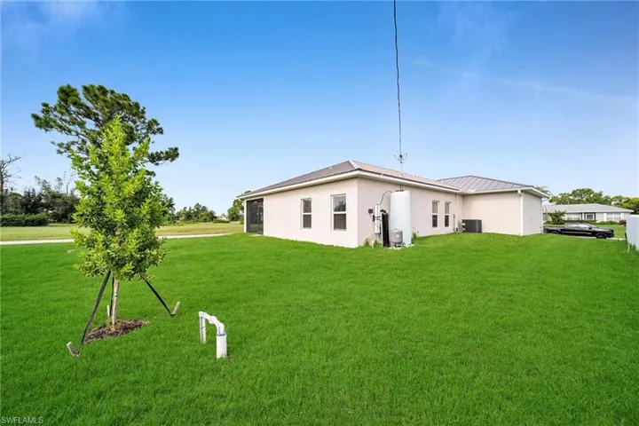 Back of house featuring a yard and central AC unit