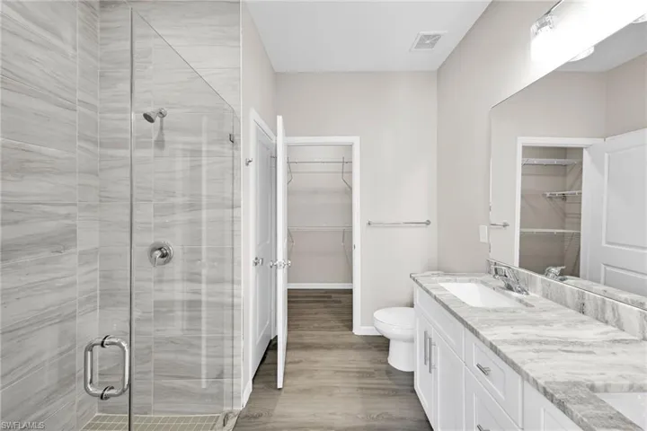 Bathroom with toilet, vanity, a shower with shower door, and wood-type flooring