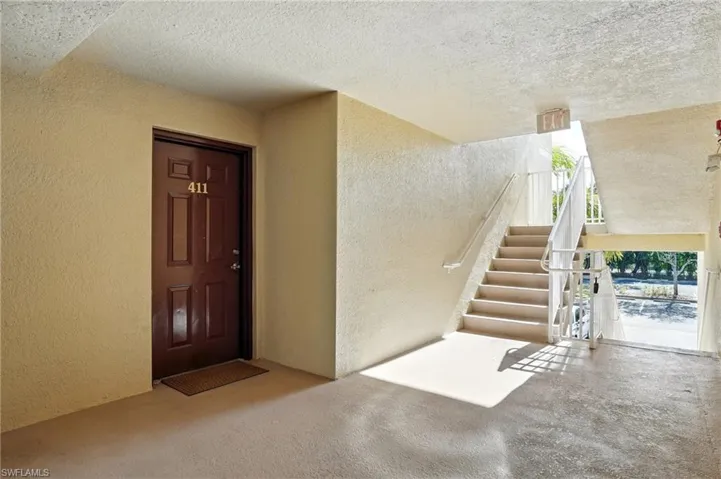 Carpeted entryway featuring a textured wall, stairs, and a textured ceiling