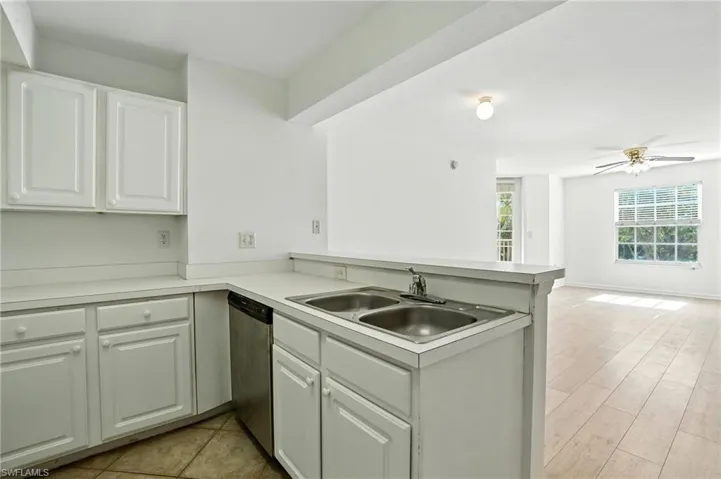 Kitchen featuring white cabinetry, light countertops, a peninsula, dishwasher, and a ceiling fan