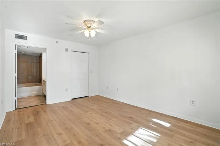 Unfurnished bedroom featuring light wood finished floors, a ceiling fan, a closet, and connected bathroom
