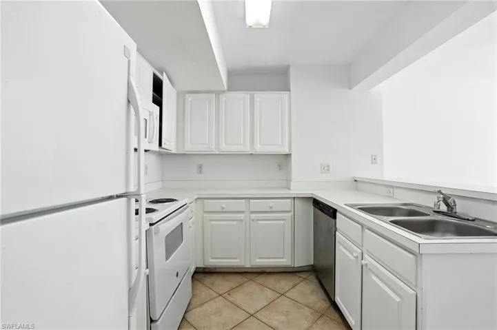 Kitchen featuring white appliances, light countertops, and white cabinets