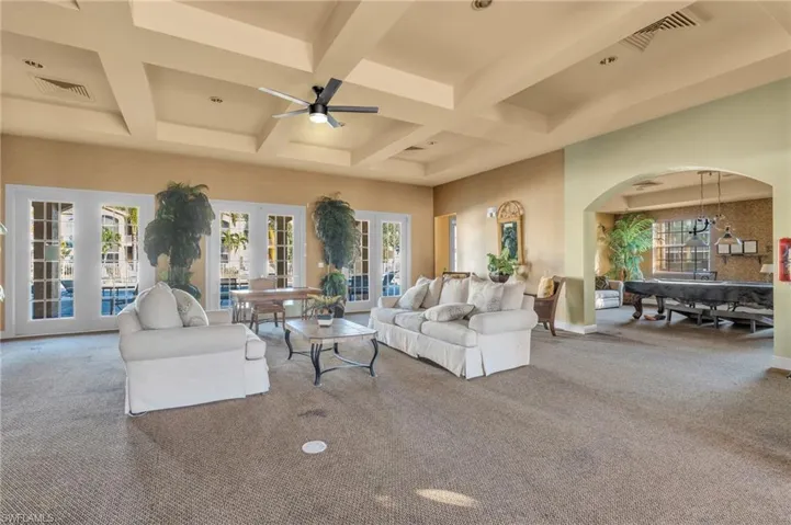Living room with carpet flooring, french doors, beam ceiling, coffered ceiling, and arched walkways