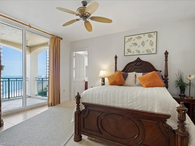 Bedroom featuring access to exterior, light tile patterned floors, a ceiling fan, and a wall of windows