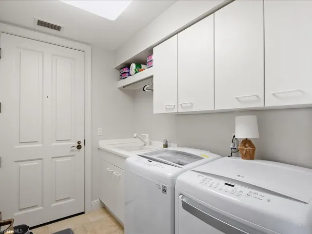 Laundry room with separate washer and dryer, cabinet space, and light tile patterned floors