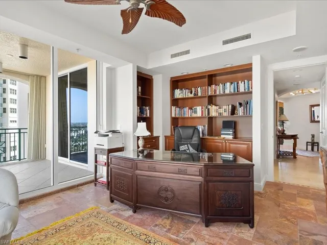 Office featuring built in shelves, a ceiling fan, stone tile floors, and a textured ceiling