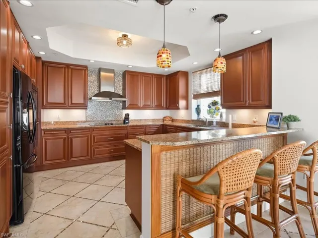 Kitchen with decorative light fixtures, a breakfast bar area, a tray ceiling, and recessed lighting