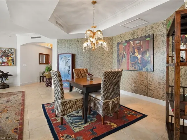 Dining area with arched walkways, crown molding, light tile patterned floors, wallpapered walls, and a chandelier