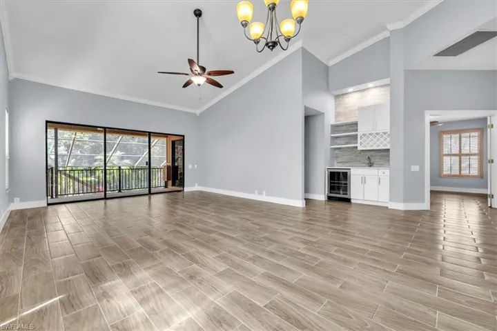 Spacious interior with vaulted ceilings, wood-finish flooring, and a built-in wet bar featuring a beverage cooler