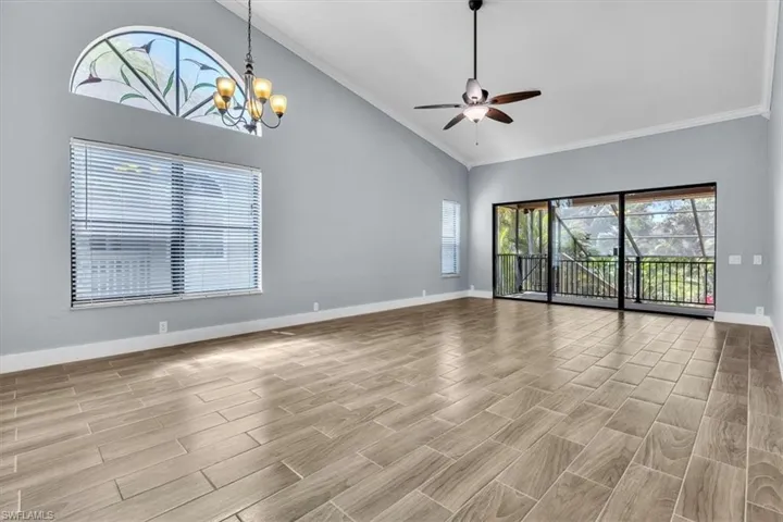 Spacious room featuring wood-finish tile flooring, vaulted ceilings, and crown molding