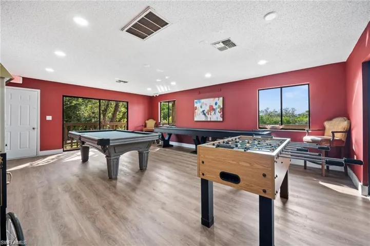Spacious recreation room featuring wood-finish flooring, recessed lighting, and expansive windows