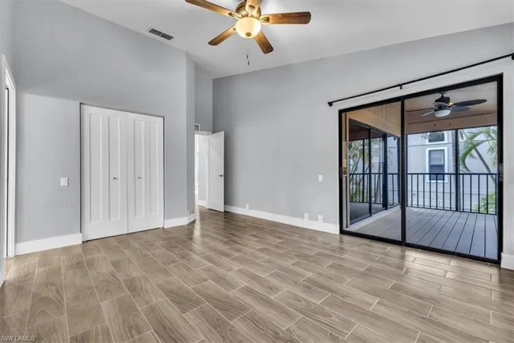 Spacious room featuring wood-finish flooring, vaulted ceilings, and a ceiling fan