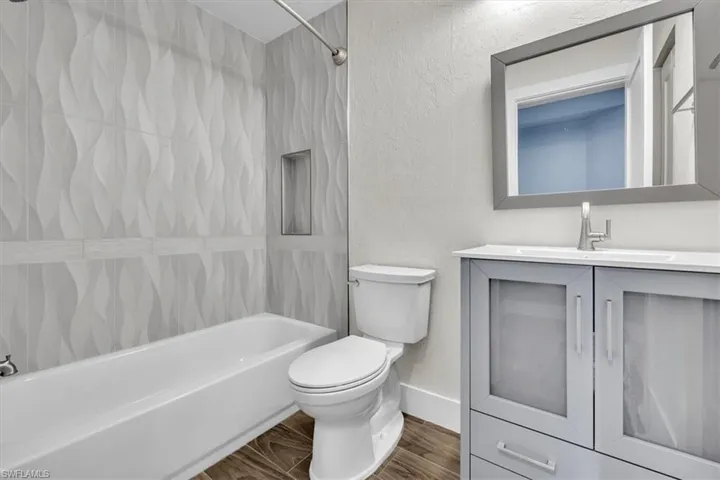 Bathroom featuring a white bathtub, toilet, and a vanity with a white countertop
