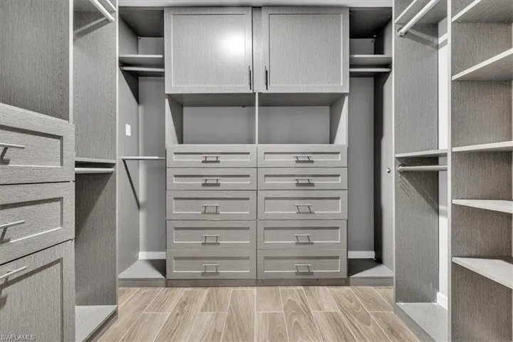 Custom closet system featuring ample built-in cabinetry, shelving, and hanging rods