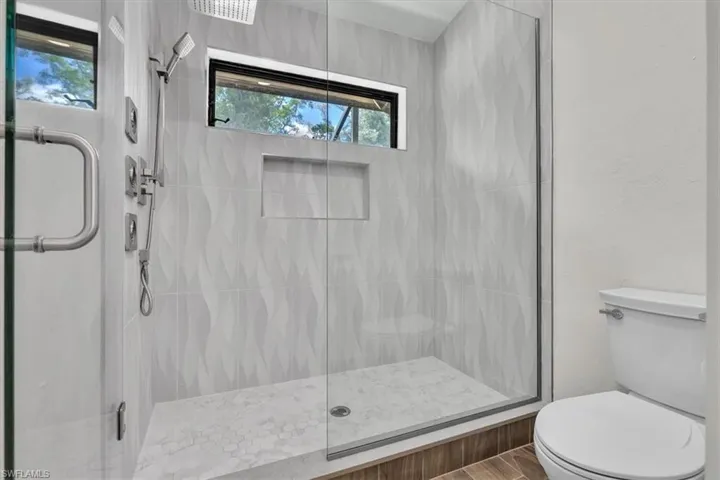 Walk-in shower with clear glass enclosure, a built-in bench, and a niche for storage