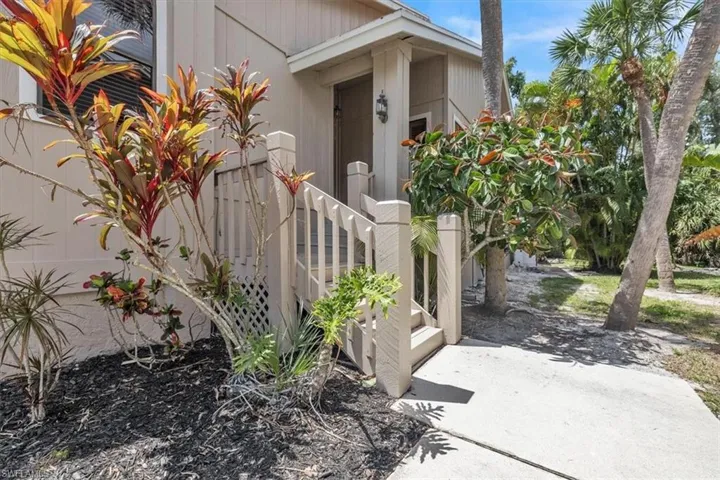 Exterior entry featuring a concrete pathway, covered porch, and exterior lighting fixture