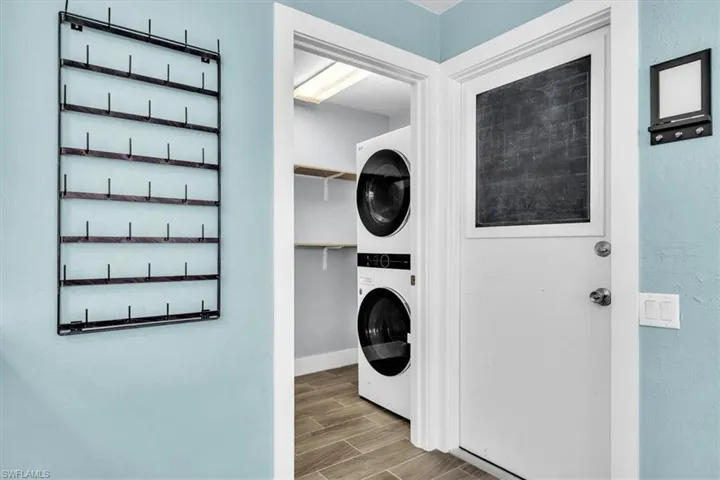 Dedicated laundry area featuring stacked appliances and wood-look flooring