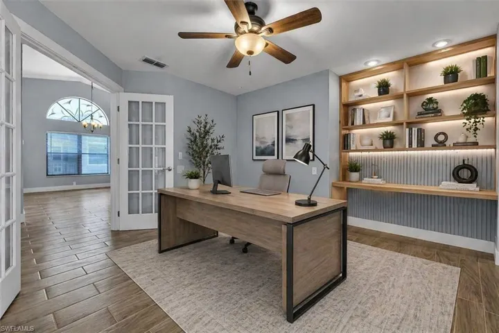 Virtually Staged-Built-in shelving with integrated lighting, wood-finish flooring, ceiling fan, and French doors