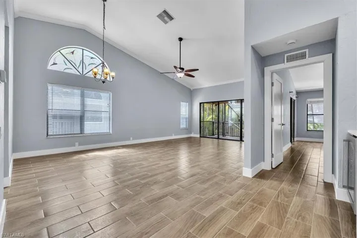 Spacious interior featuring vaulted ceilings, wood-finish tile flooring, and a decorative arched transom window