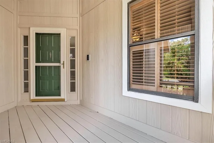 Inviting porch entry featuring a green panel door with a storm door, flanked by narrow sidelight windows