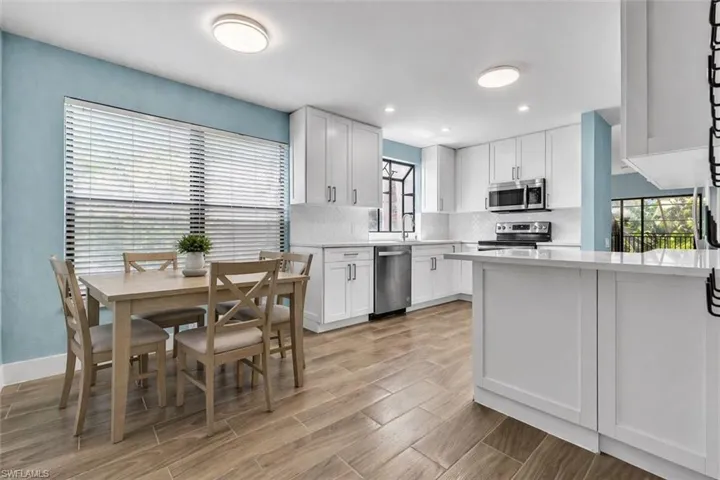 Virtually Staged Modern kitchen featuring white shaker cabinetry, stainless steel appliances, a white subway tile backsplash, and light wood-finish flooring