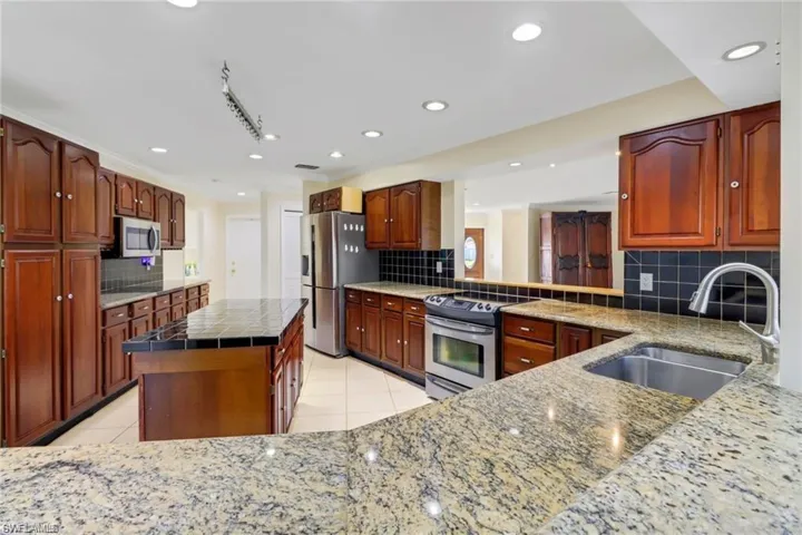 Kitchen with a center island, appliances with stainless steel finishes, light tile patterned flooring, and a sink