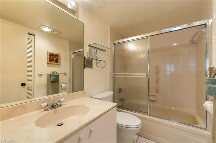 Bathroom with vanity, combined bath / shower with glass door, and light tile patterned flooring