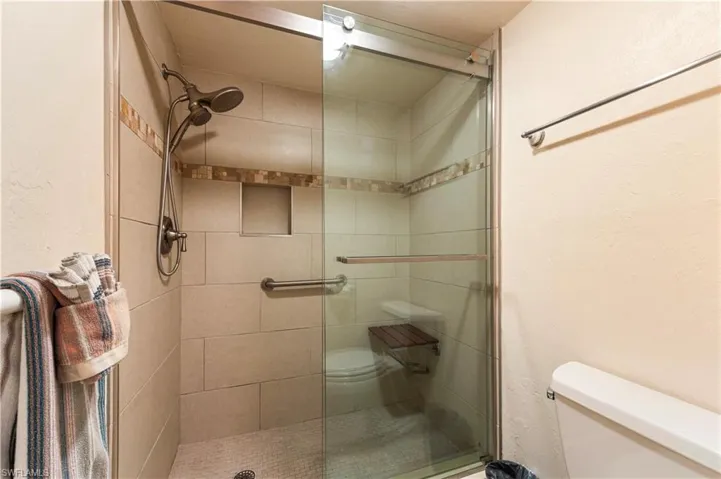 Bathroom featuring a stall shower and a textured wall