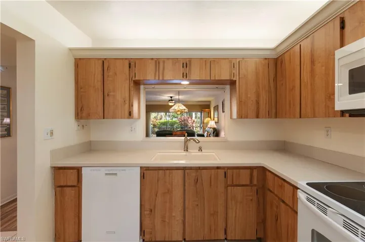 Kitchen featuring white appliances, wood finish cabinets, and light countertops