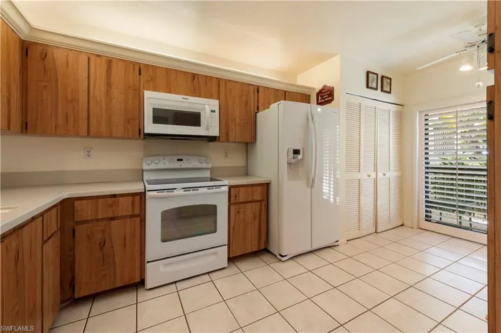 Kitchen featuring white appliances, wood finish cabinets, ceiling fan, light countertops, and light tile patterned flooring