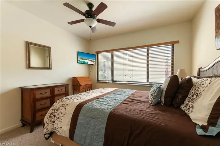 Carpeted bedroom with a ceiling fan and baseboards