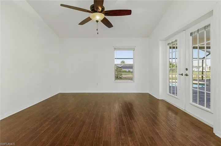 Unfurnished room with french doors, ceiling fan, wood-type flooring, and vaulted ceiling