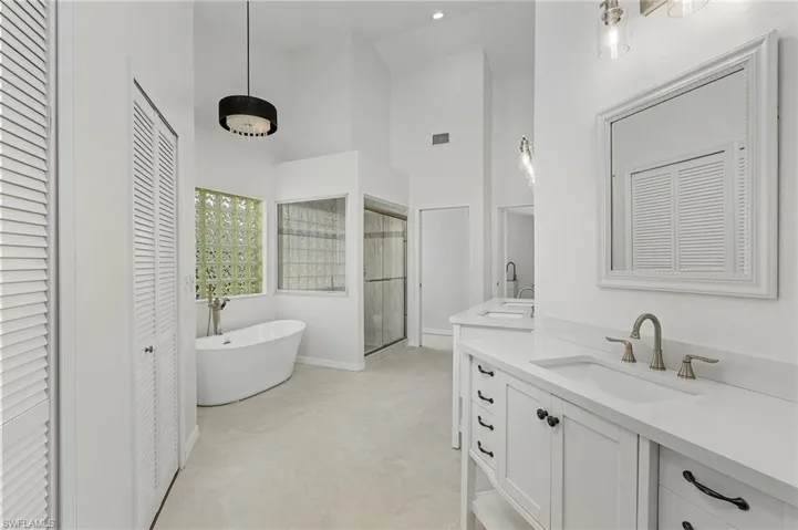 Bathroom featuring vanity, a tub to relax in, tile patterned floors, and a towering ceiling