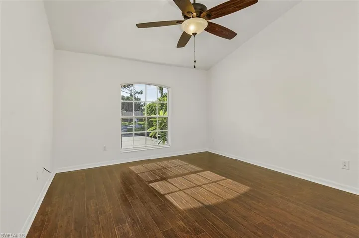 Unfurnished room featuring ceiling fan, dark hardwood / wood-style flooring, and vaulted ceiling