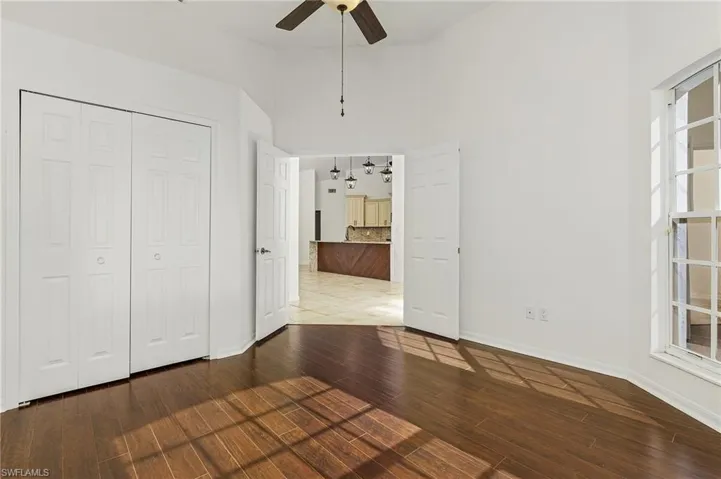 Unfurnished bedroom with a closet, tile patterned flooring, a towering ceiling, and ceiling fan