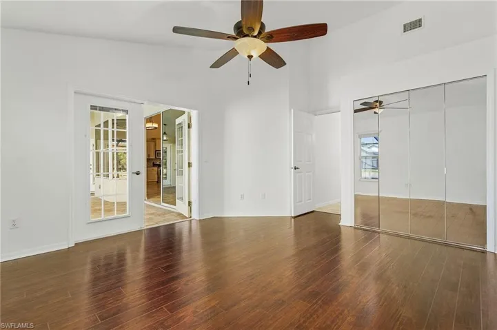 Unfurnished bedroom with high vaulted ceiling, multiple windows, ceiling fan, and hardwood / wood-style floors