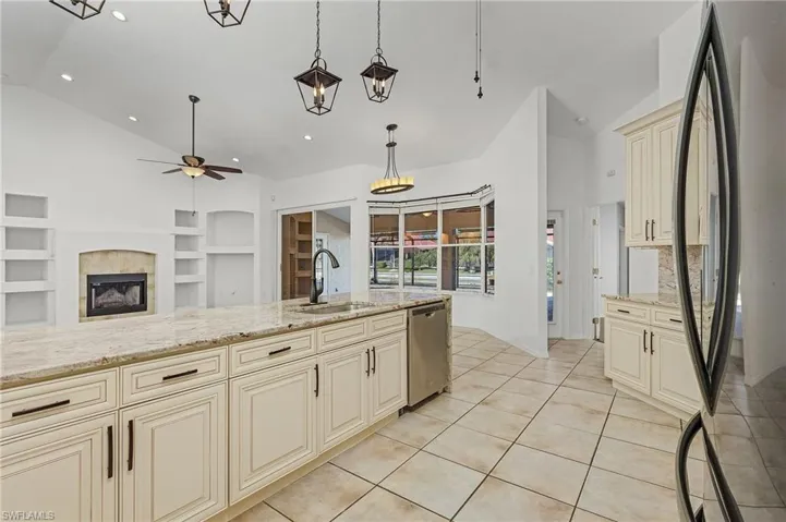 Kitchen with built in shelves, cream cabinets, stainless steel dishwasher, black fridge, and sink