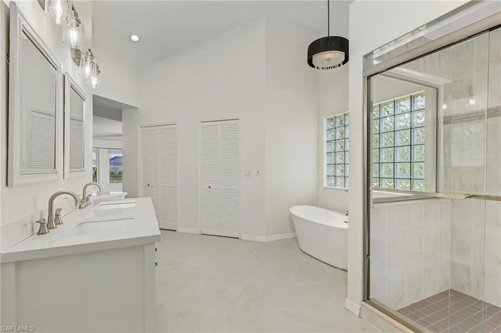 Bathroom with dual vanity, shower with separate bathtub, tile patterned floors, and a healthy amount of sunlight