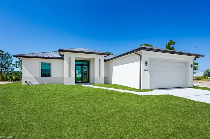 Prairie-style home with stucco siding, a front yard, and driveway