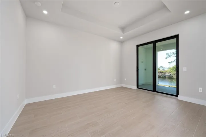 Unfurnished room with recessed lighting, light wood-type flooring, and a raised ceiling