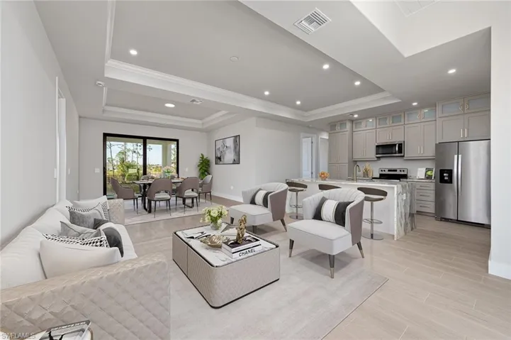 Living room with ornamental molding, wood tiled floors, recessed lighting, and a tray ceiling